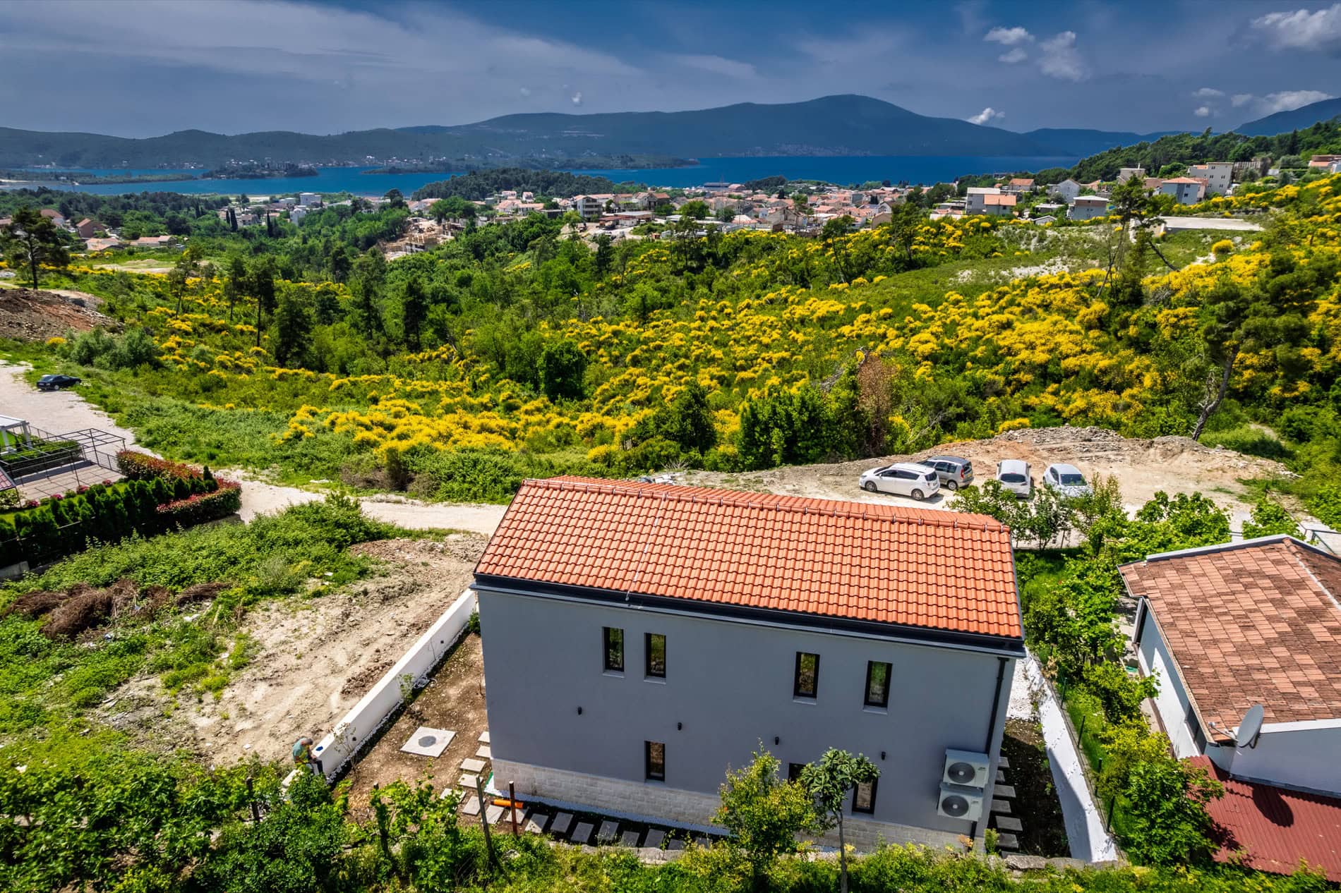 Zweistöckige Villa in Tivat, Montenegro, mit Blick auf das Meer, die Berge und die grüne Landschaft mit blühenden Sträuchern.