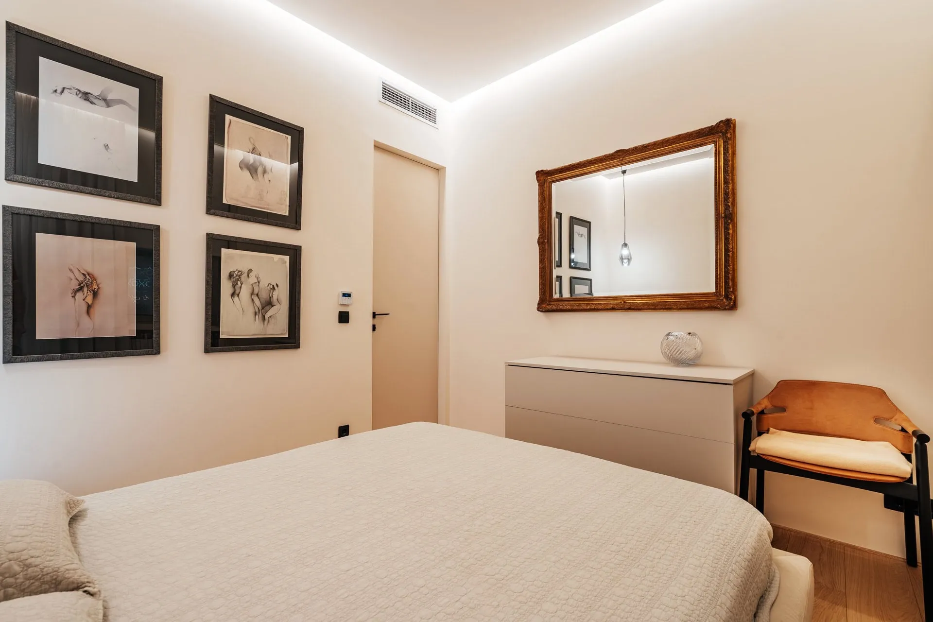 Modernes Schlafzimmer in einer Wohnung, Bečići, Montenegro: Bett, Kommode, Spiegel mit goldenem Rahmen und Wanddekoration.