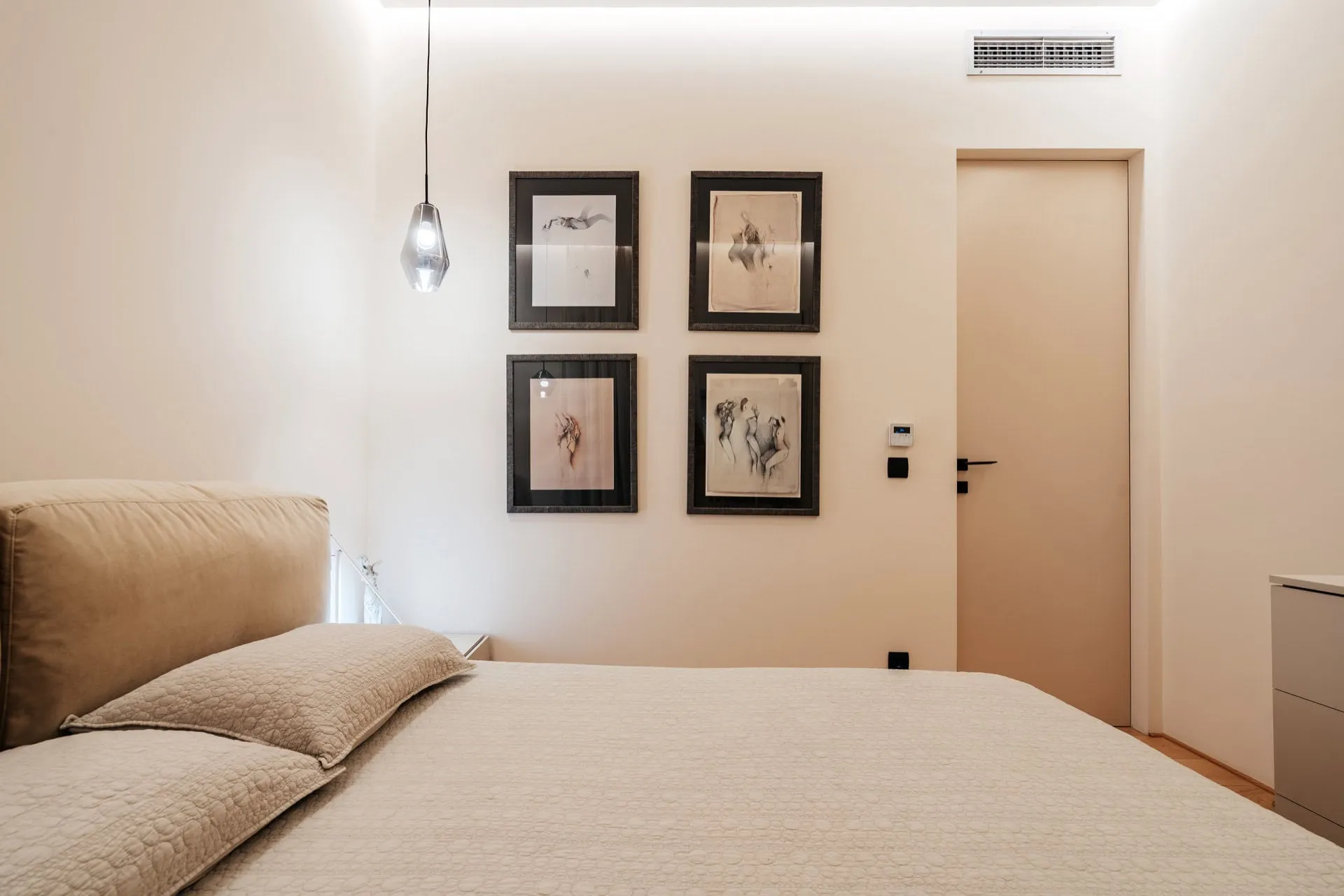 Modernes Schlafzimmer in einer Wohnung in Bečići, Montenegro: Doppelbett, Designerleuchte und Wanddekoration.
