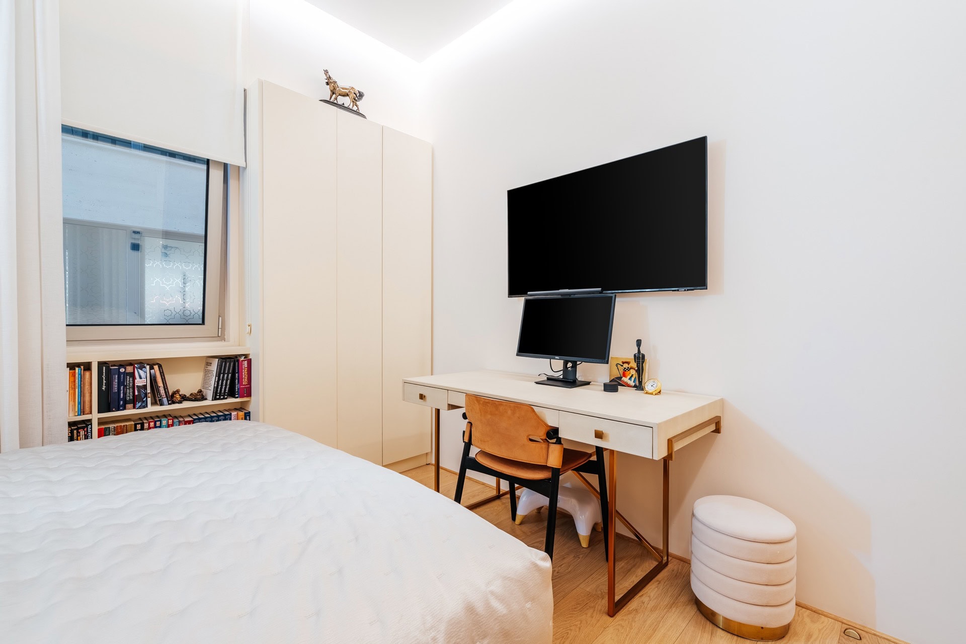 Modernes Schlafzimmer mit Arbeitsplatz in einer Wohnung in Bečići, Montenegro: Bett, Schreibtisch, TV und Kleiderschrank.