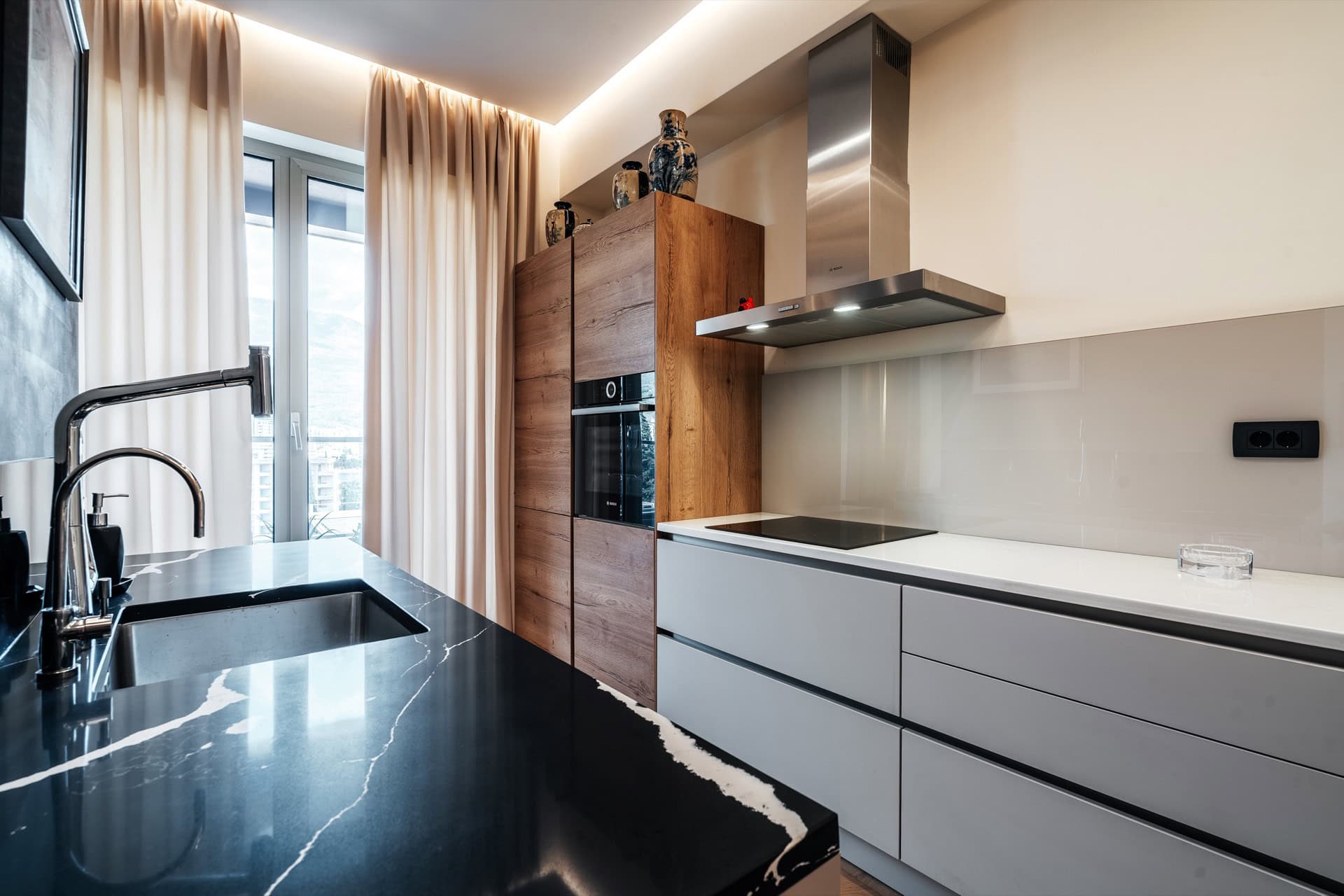 Moderne Küche in einer Wohnung in Bečići, Montenegro: stilvolle Einbauküche, schwarze Marmorarbeitsplatte und integrierte Geräte.