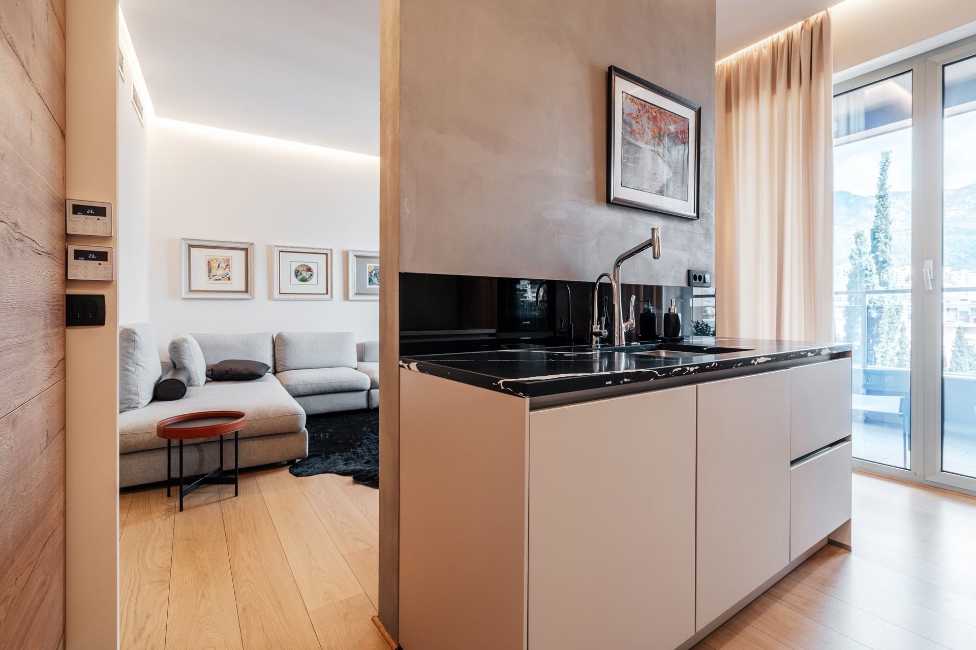 Moderne Küche mit schwarzer Arbeitsplatte und Wohnzimmer in einer Wohnung in Bečići, Montenegro, mit Zugang zum Balkon und Aussicht.