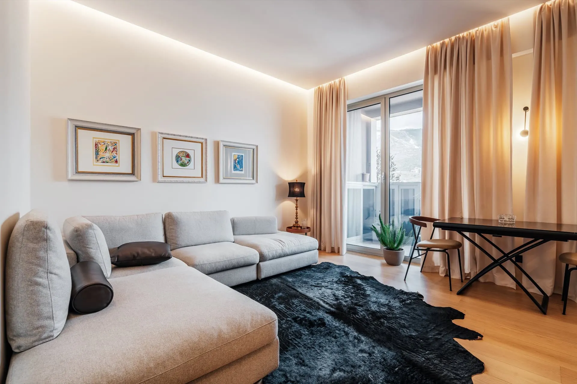 Modernes Wohnzimmer mit grauem Sofa und Zugang zum Balkon in einer Wohnung in Bečići, Montenegro.