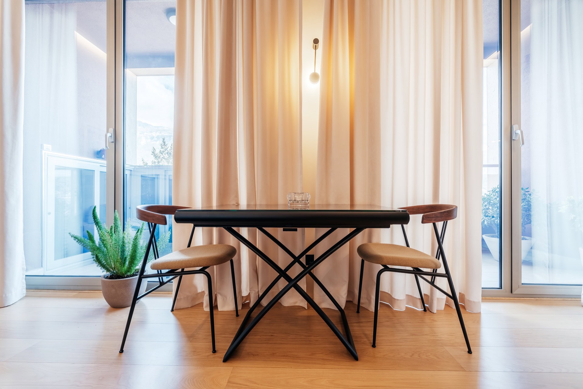 Essbereich mit schwarzem Tisch und Stühlen in einer modernen Wohnung in Bečići, Montenegro, mit Zugang zur Terrasse.