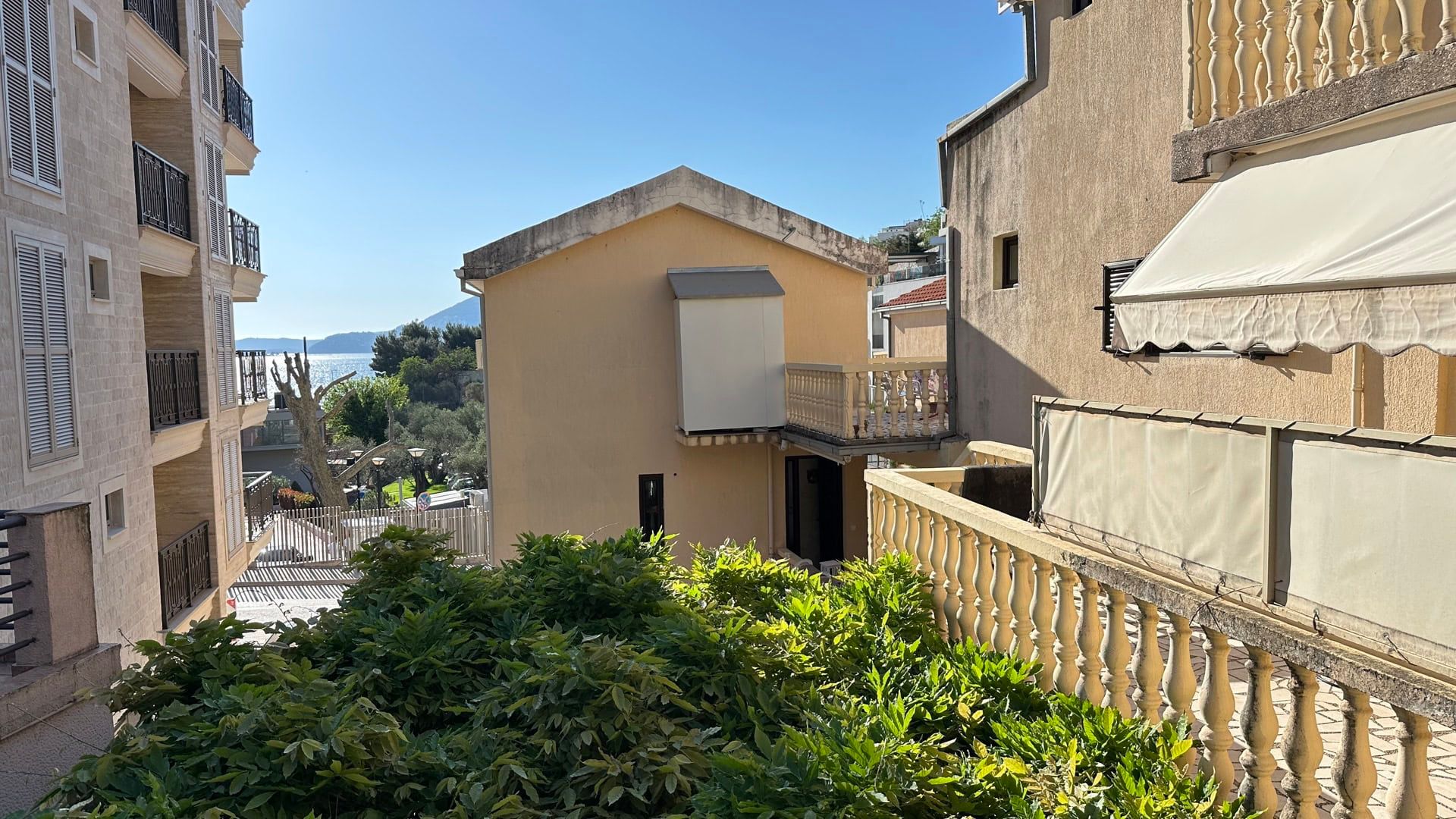 View from the hotel terrace in Pržno, Montenegro: stone balustrades, neighboring buildings, and a partial view of the sea and greenery.