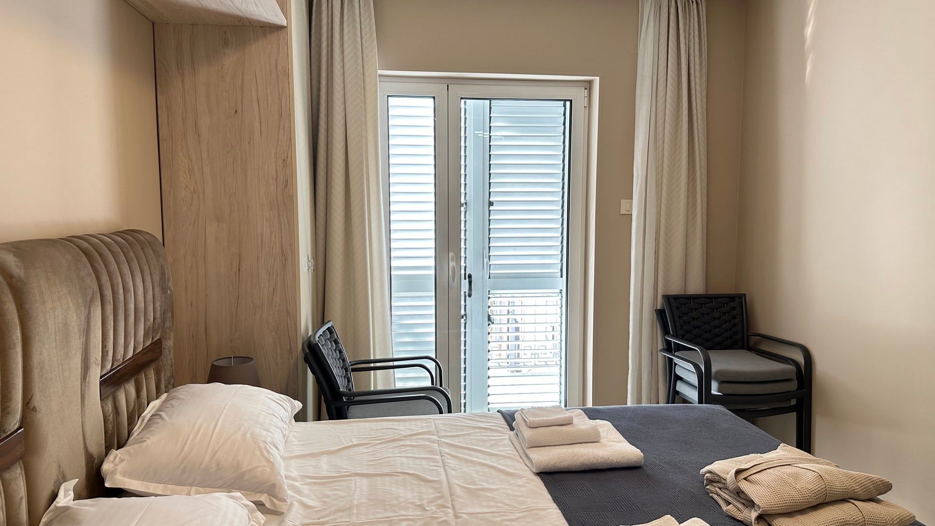 Cozy bedroom in a hotel in Pržno, Montenegro: double bed, modern furniture, and access to a balcony with blinds.
