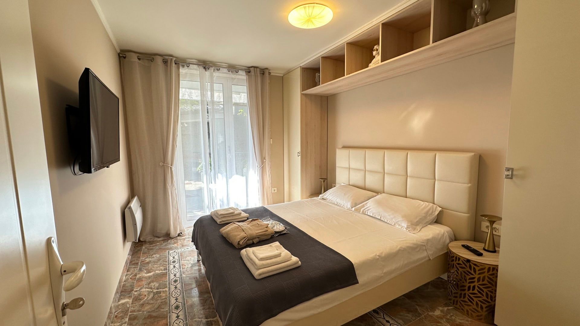 Cozy bedroom with a double bed in a hotel in Pržno, Montenegro: light furniture, TV, and access to the terrace.