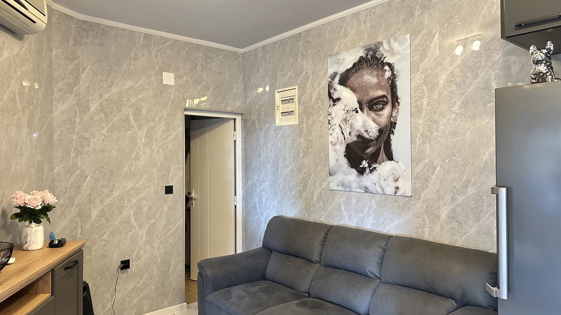 Hotel living room in Pržno, Montenegro: gray sofa, marble-finish walls, and a stylish poster on the wall.