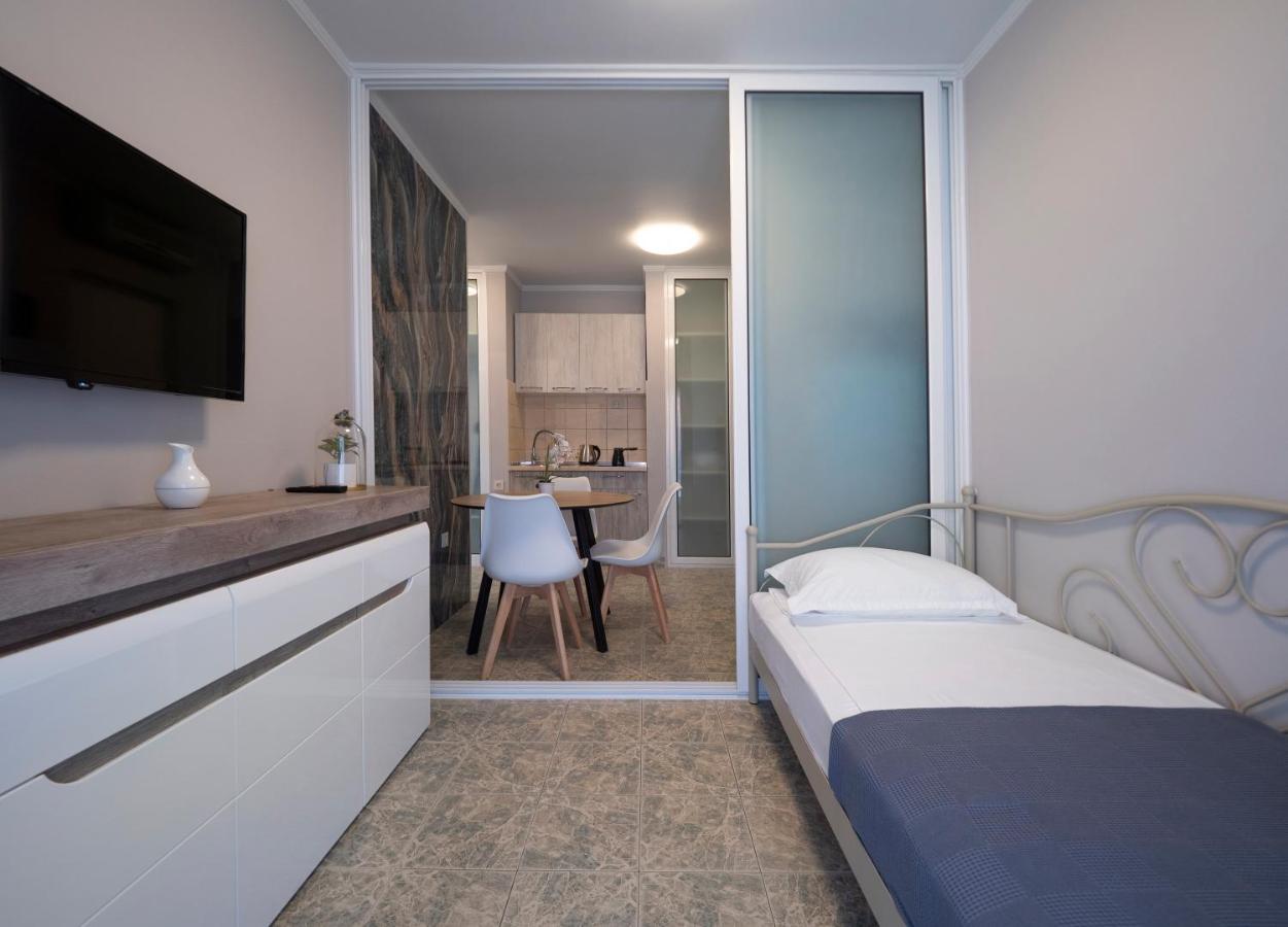 Bedroom interior with a bed and kitchenette area in a hotel in Pržno, Montenegro: modern furniture and tiled floor.