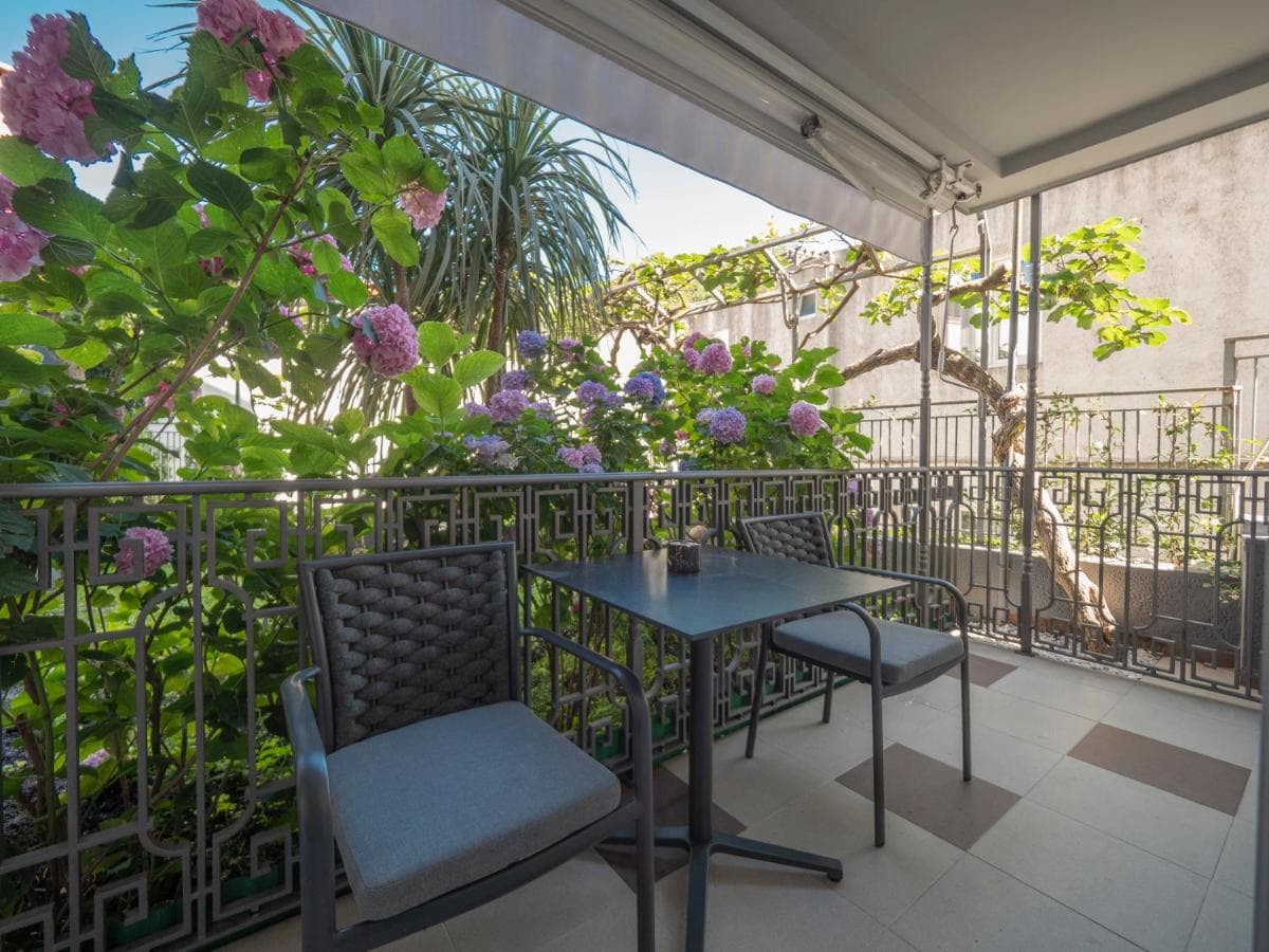 Cozy balcony with garden furniture and blooming hydrangeas at a hotel in Pržno, Montenegro. View of a green terrace.