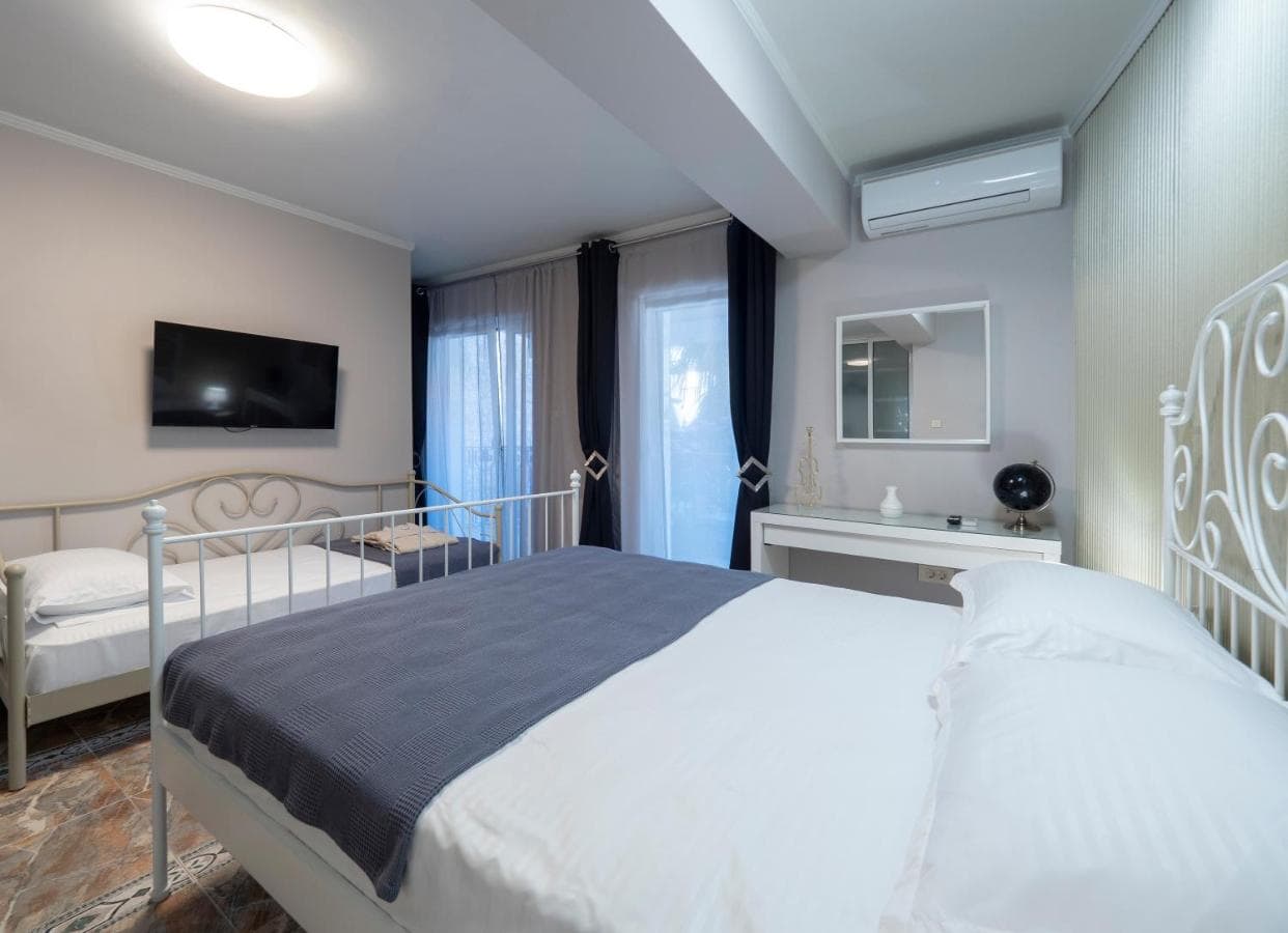 Bright bedroom with a double bed in a hotel in Pržno, Montenegro: modern furniture, TV, air conditioning, and access to the balcony.