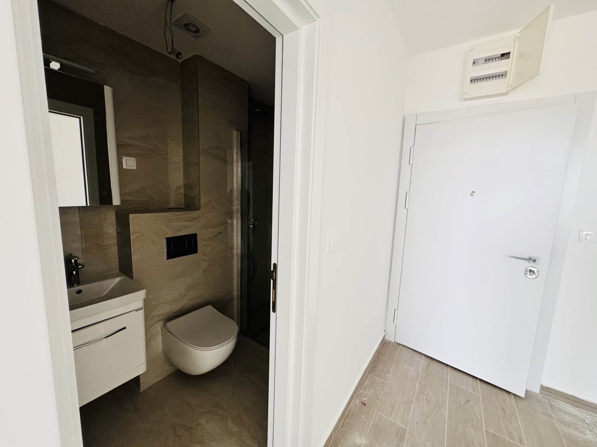 Savremeno kupatilo sa tuš kabinom i belim nameštajem u novom stanu u Bečićima, Crna Gora.