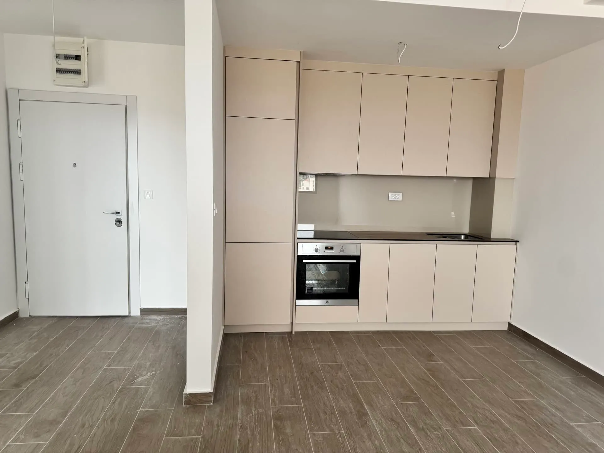 Moderne Küche in einer neuen Wohnung in Bečići, Montenegro: beiger Küchenblock, Einbaugeräte und Bodenfliesen.