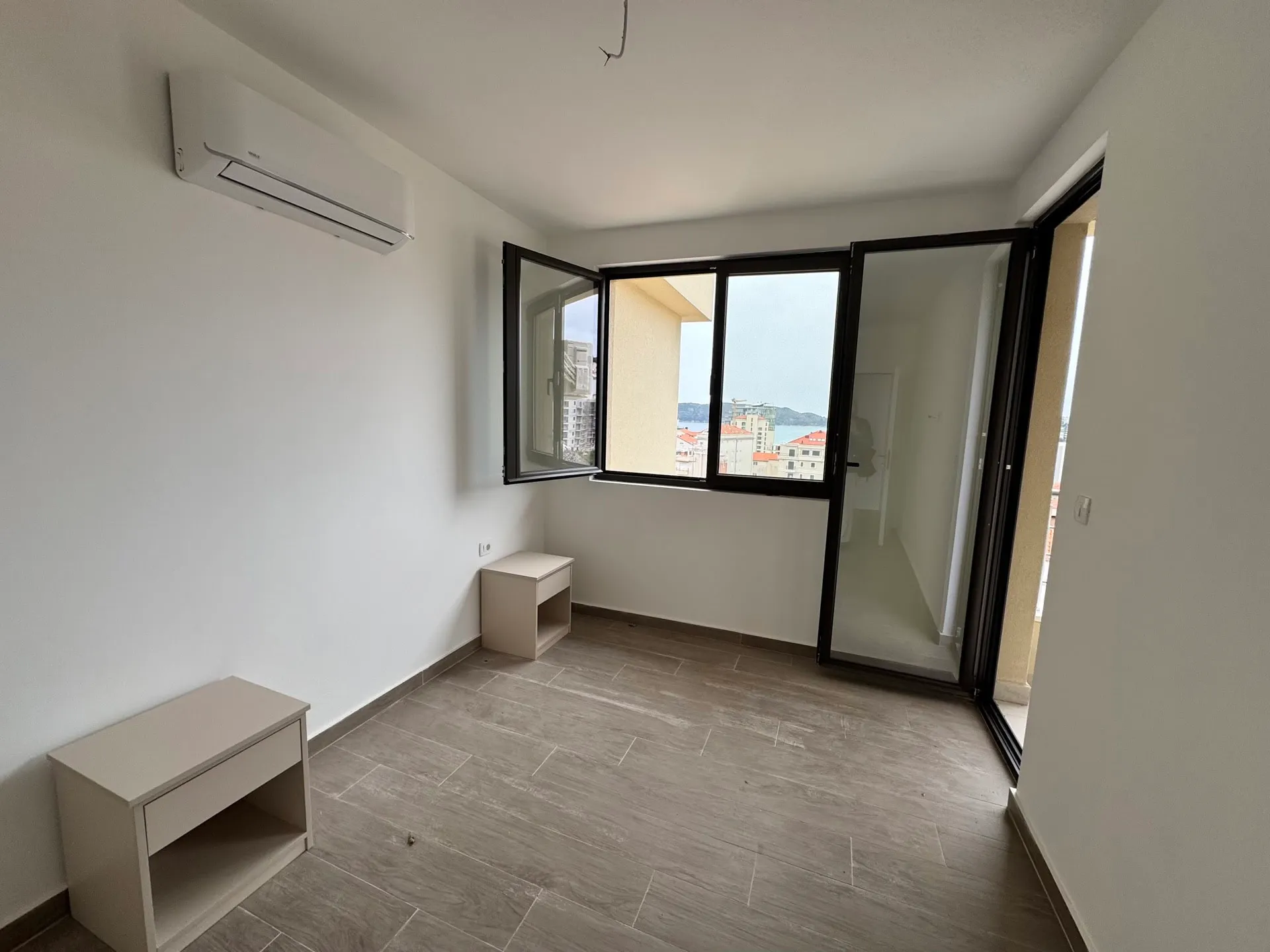 Helles Schlafzimmer in einer Wohnung in Bečići, Montenegro: Panoramafenster mit Meerblick, Klimaanlage und Fliesenboden.