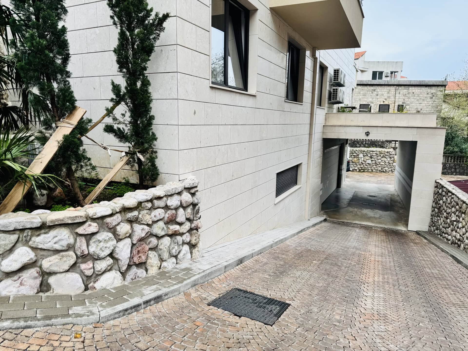 Modern residential building with stone cladding and entrance to underground parking in Bečići, Montenegro.