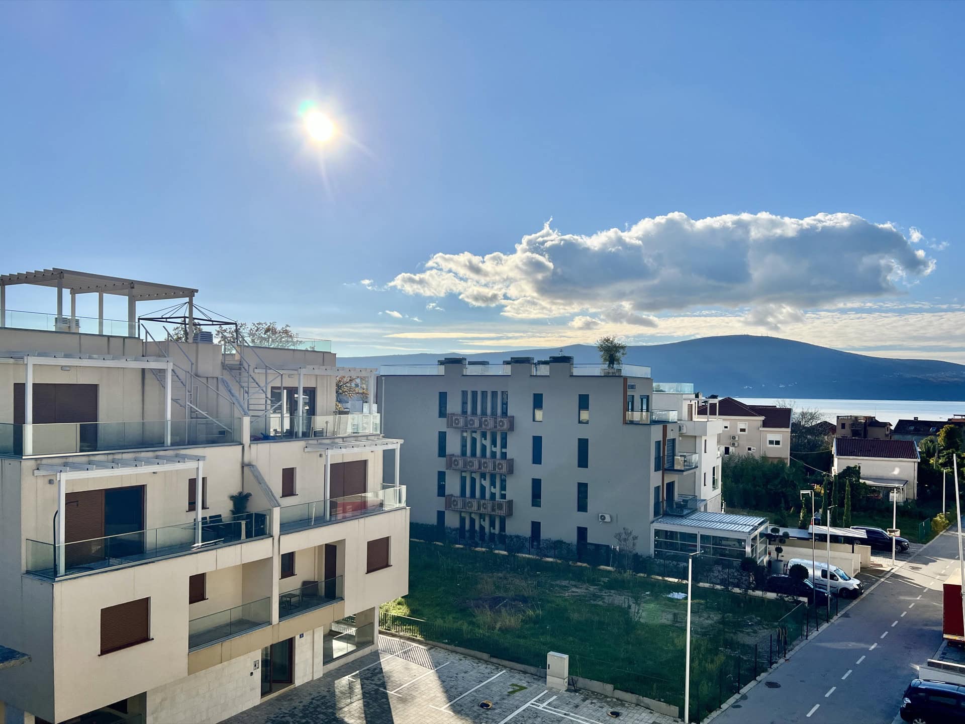 Pogled na moderne stambene komplekse u Tivtu, Crna Gora, sa terasama i panoramskim pogledom na planine i more.