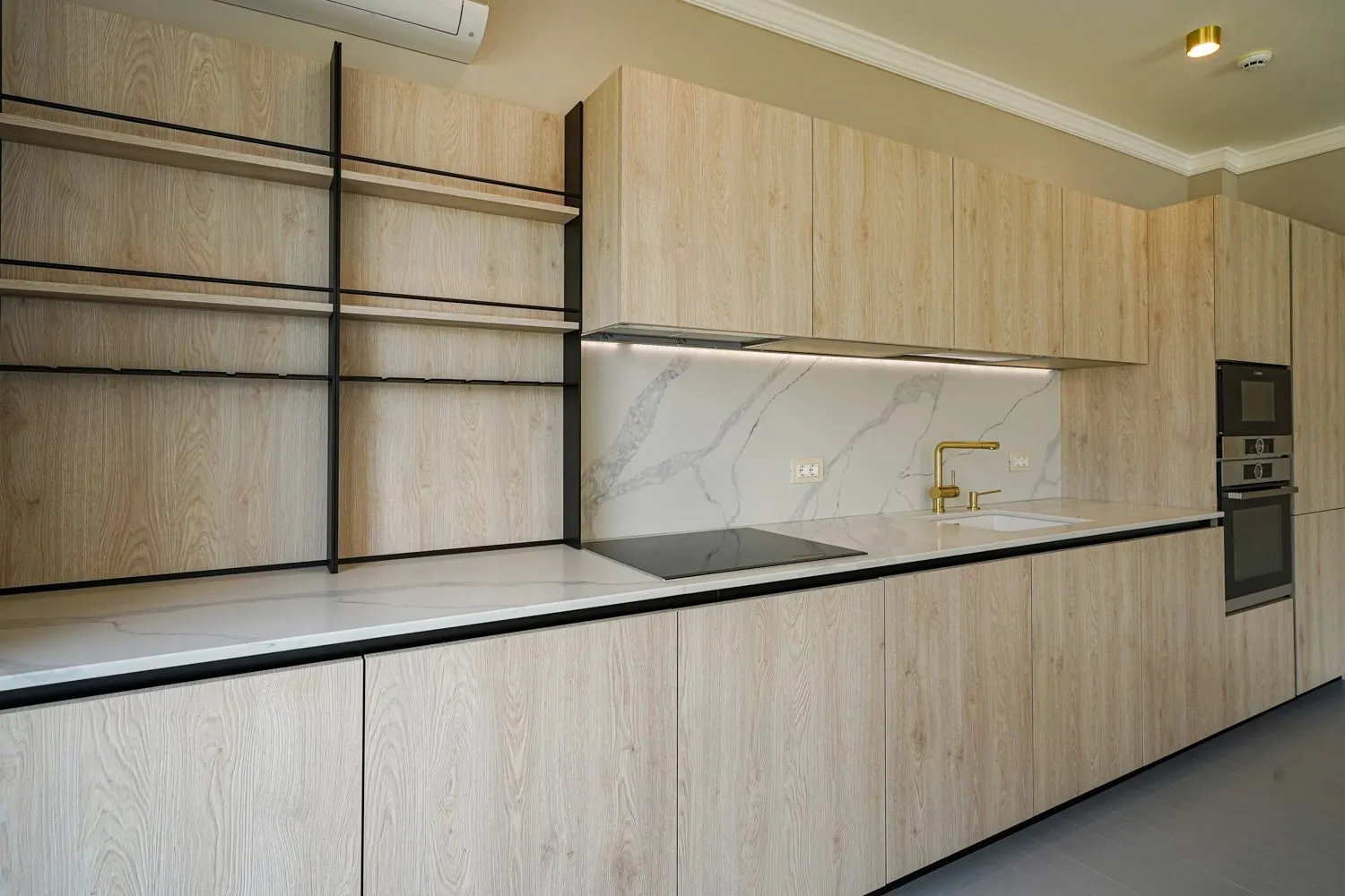 Moderne Küche in einer Wohnung in Dobrota, Montenegro: Holzoptik-Fronten, Marmor-Rückwand und Einbaugeräte.