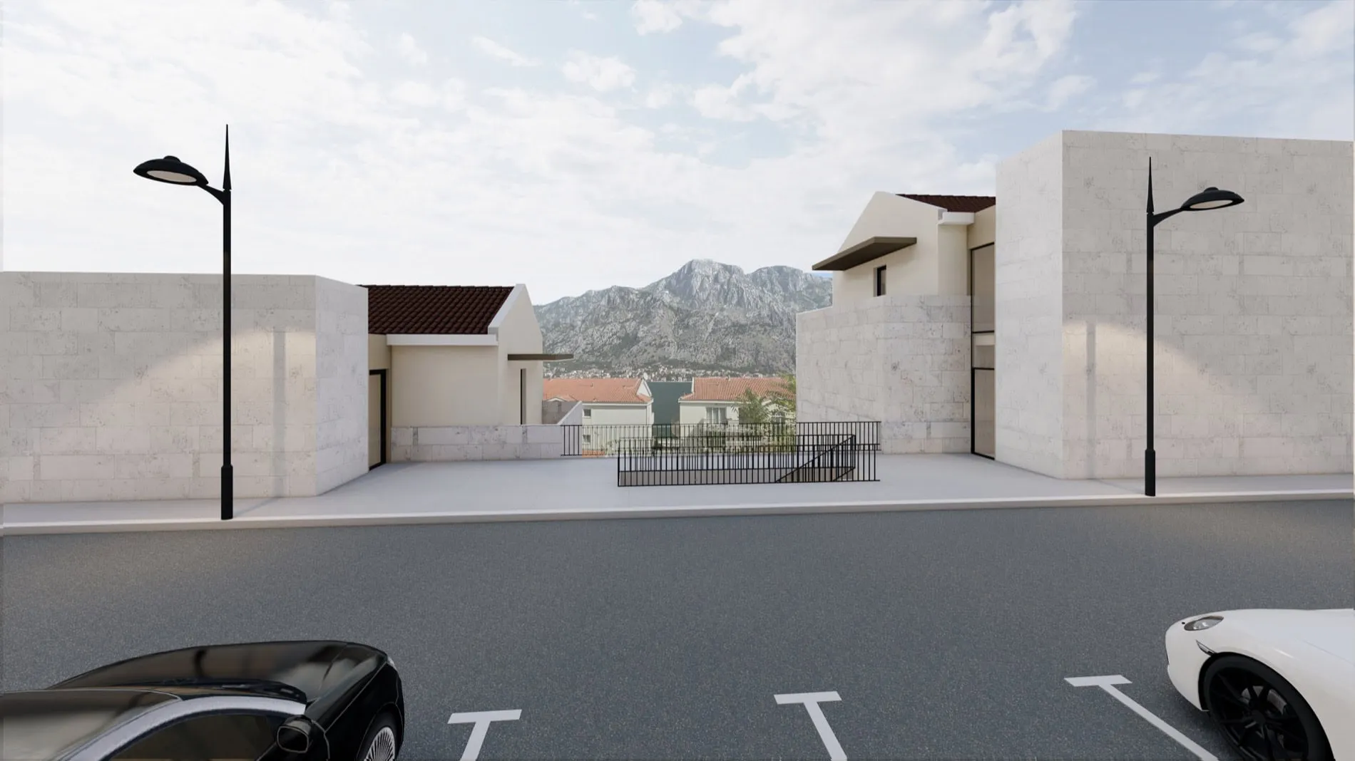 Street view with parking, white stone walls, street lamps, and mountains in the background.