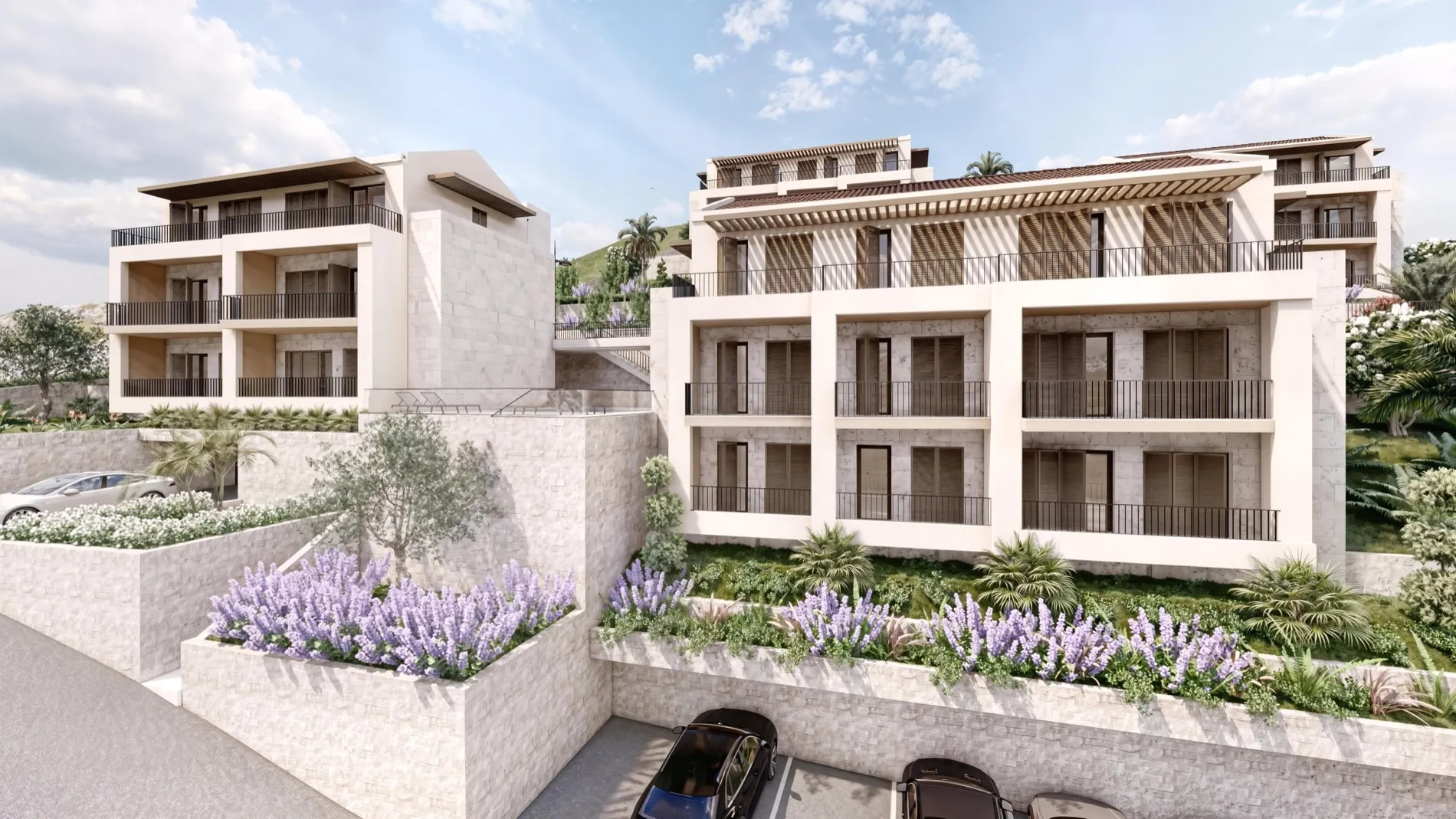 Modern residential complex exterior with balconies, stone walls, and purple flower beds.