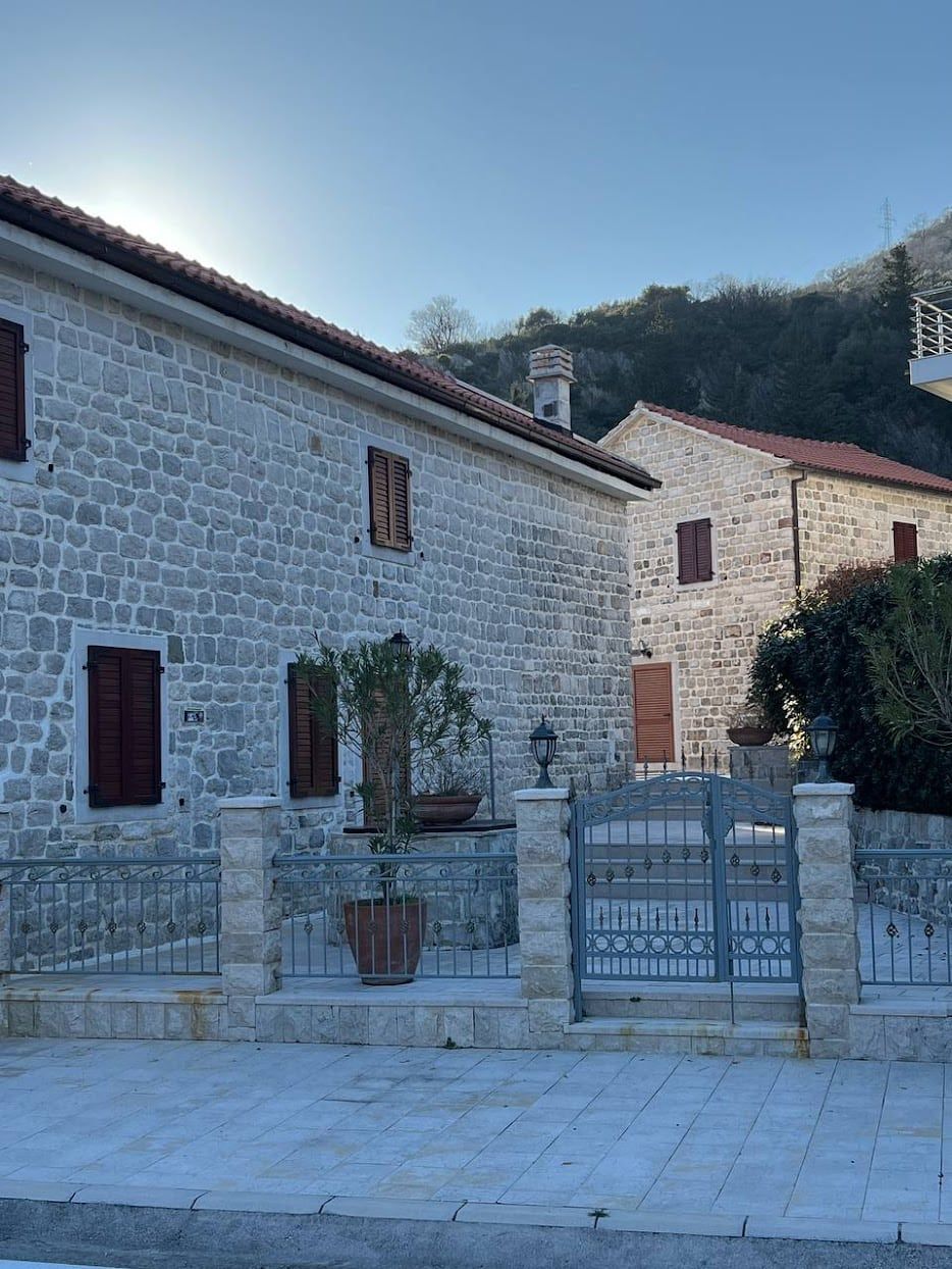 Traditional stone villa in Kamenari, Montenegro: natural stone facade, wrought-iron gates, and a cozy courtyard.