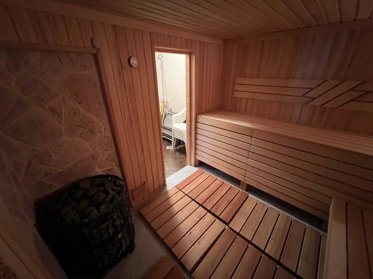 Drewniana sauna z kamiennym wykończeniem w willi w Kamenari, Czarnogóra: wnętrze łaźni parowej z półkami i piecem kamiennym.