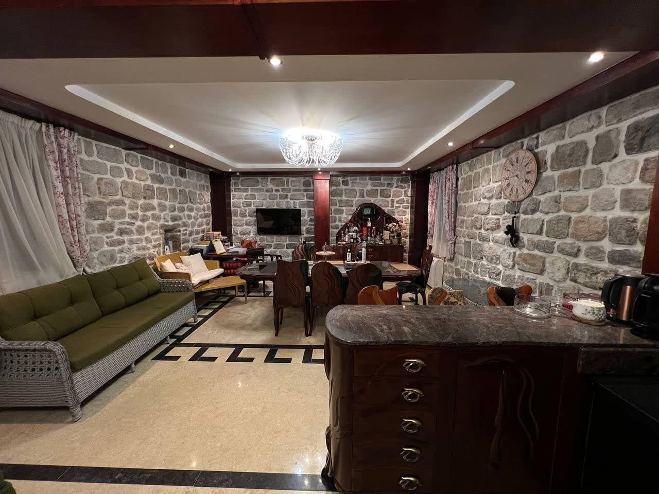 Living room with natural stone finishes in a villa, Kamenari, Montenegro: soft seating, dining area, and bar counter.