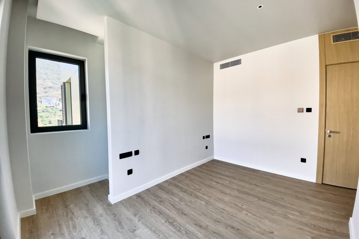 Helles Schlafzimmer mit Laminat und Bergblick in einer neuen Wohnung in Tivat, Montenegro. Moderne Ausstattung und Einrichtung.