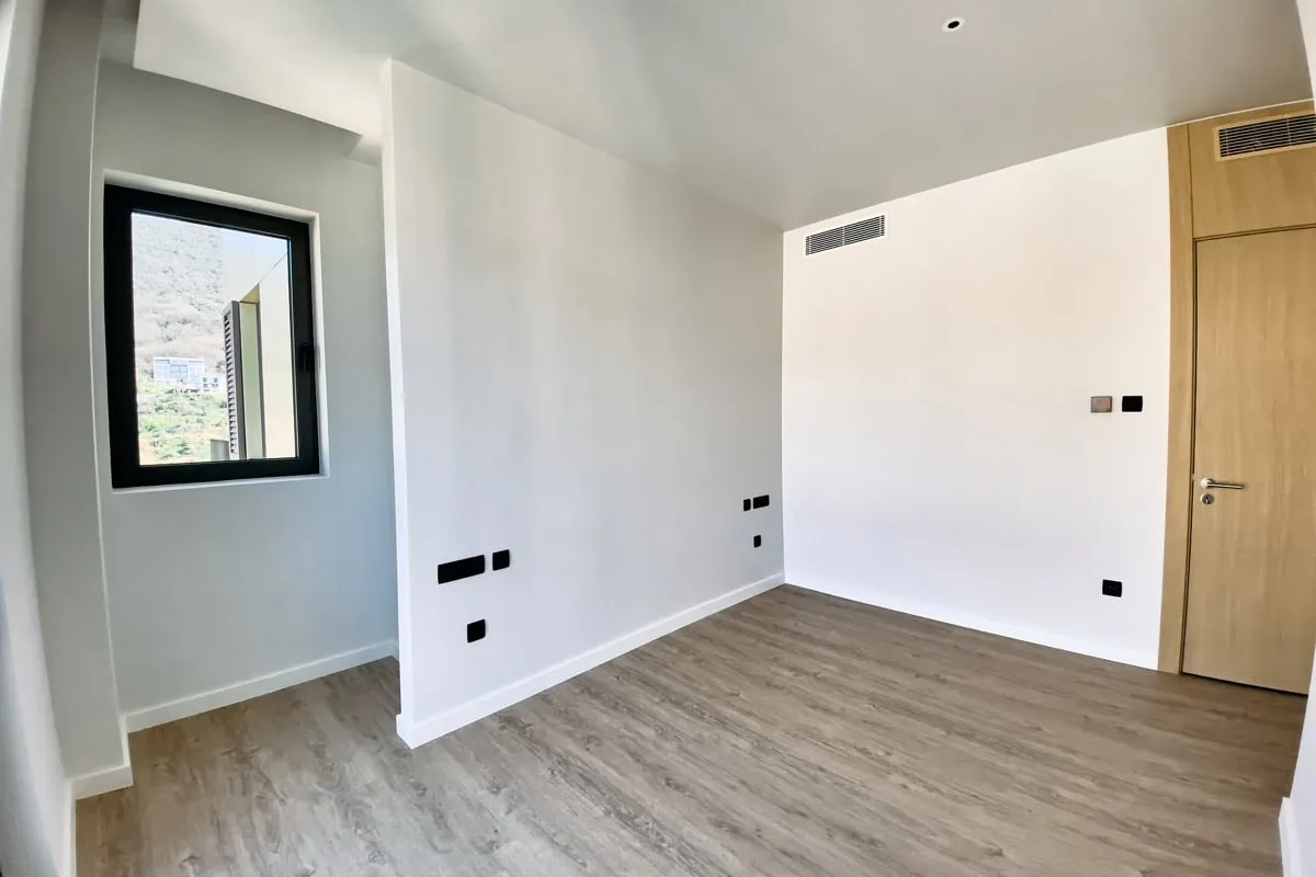 Helles Schlafzimmer mit Laminat und Bergblick in einer neuen Wohnung in Tivat, Montenegro. Moderne Ausstattung und Einrichtung.