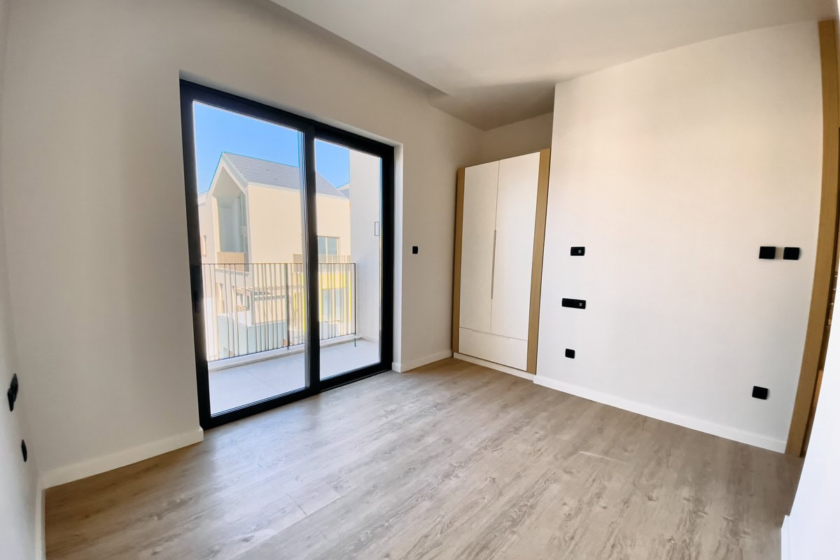 Helles Schlafzimmer in einer Wohnung in Tivat, Montenegro: Panoramafenster, Zugang zum Balkon, Einbauschrank und Laminatboden.