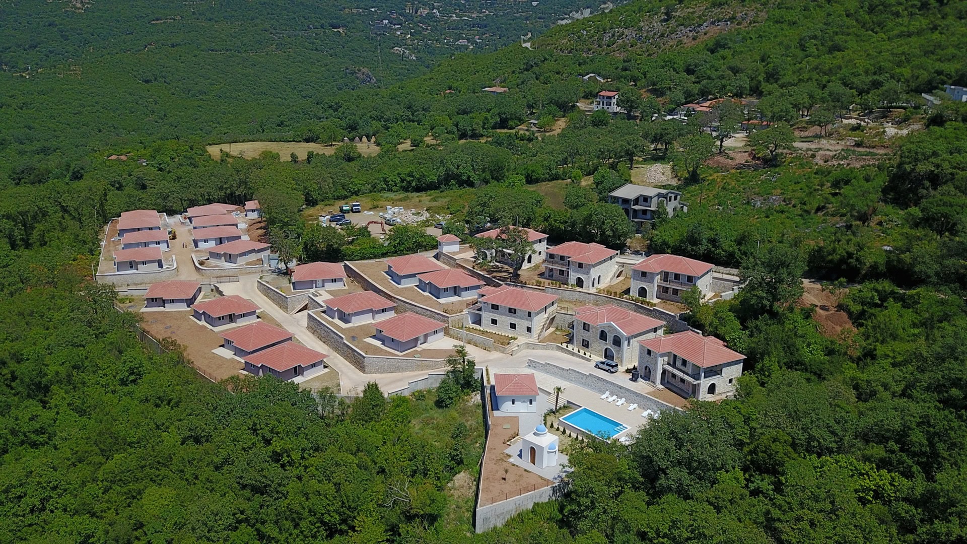 Pogled iz vazduha na stambeni kompleks sa vilama, bazenom i kamenim oblogama, okružen planinama i šumama, Bar, Crna Gora