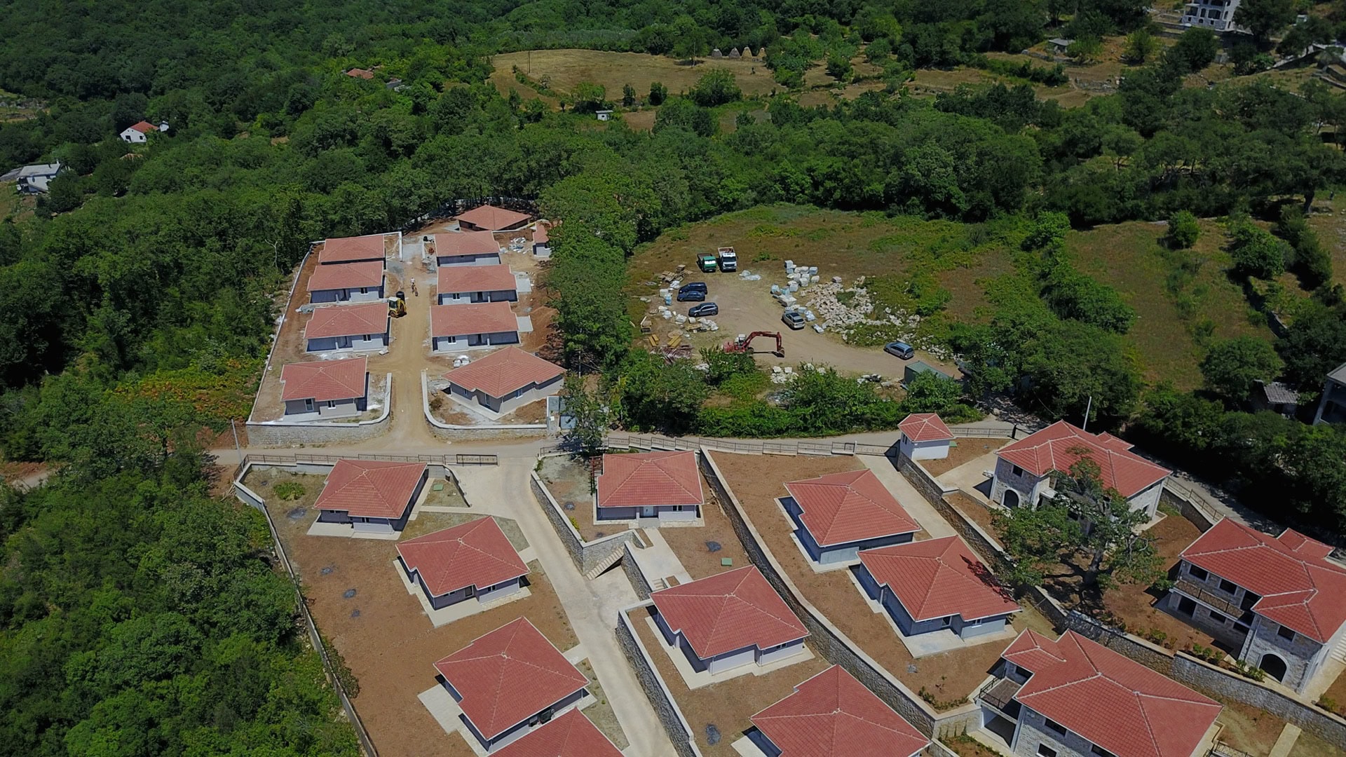 Pogled iz vazduha na izgradnju stambenog naselja sa krovovima od crepa, okruženog šumom, Bar, Crna Gora.