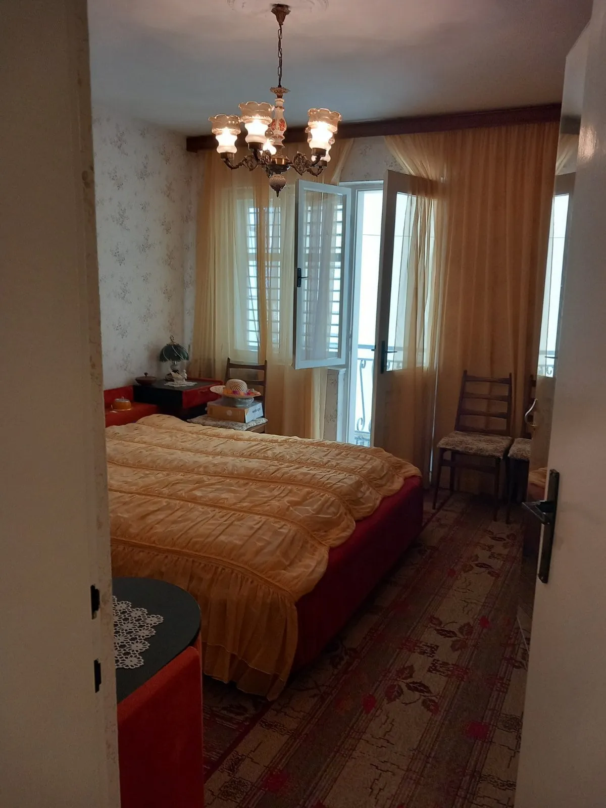 Gemütliches Schlafzimmer mit Doppelbett und Zugang zum Balkon in einem Haus, Stadt Igalo, Montenegro. Klassisches Interieur.