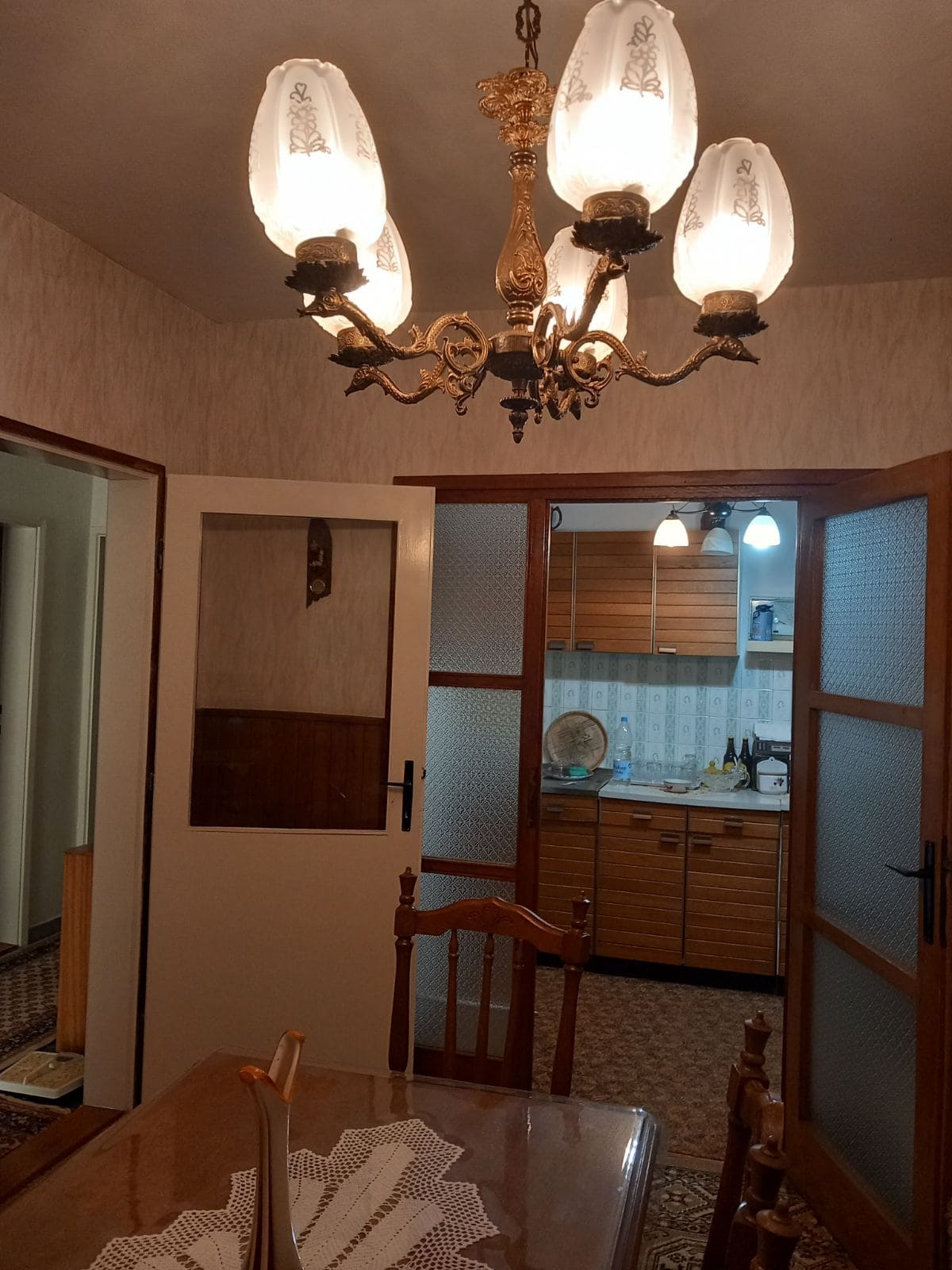 Living room interior with a vintage chandelier and a view of the kitchen in a house, Igalo, Montenegro. Wooden doors and furniture.