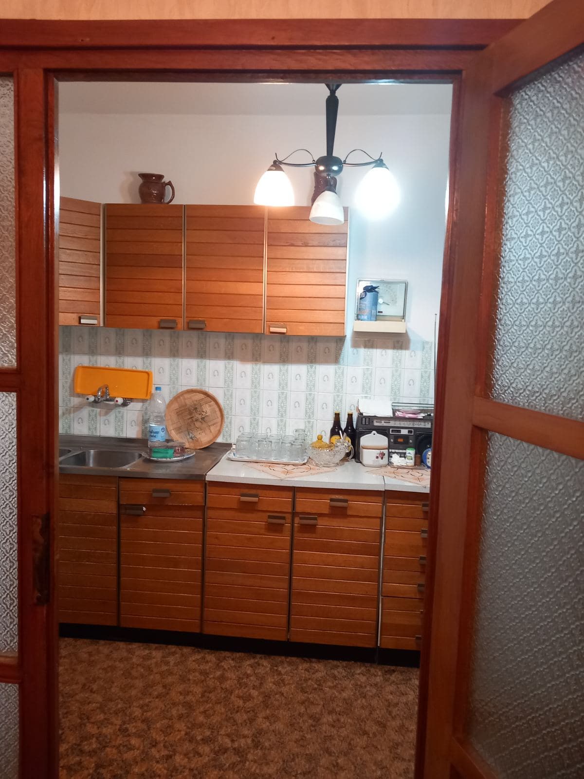 Kitchen with wooden cabinetry in a house for sale in Igalo, Montenegro: view of the work area and dining furniture.