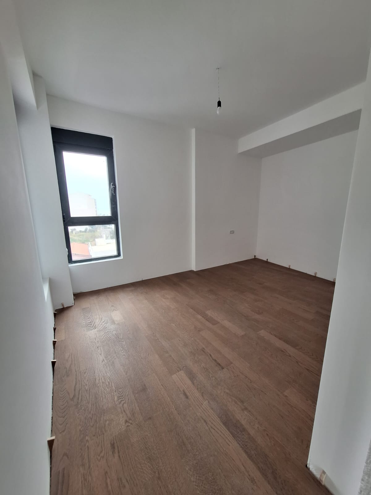 Yeni dairede parke zeminli aydınlık yatak odası, Bar, Karadağ. Pencereden şehir manzarası.