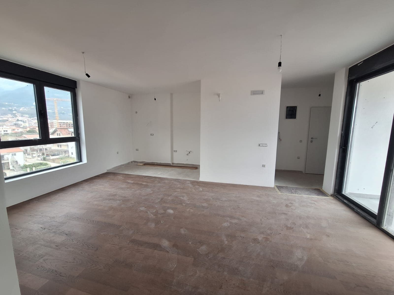 Bar, Karadağ’daki yeni dairede, panoramik pencereli ve parke zeminli aydınlık oturma odası, bitmemiş halde.