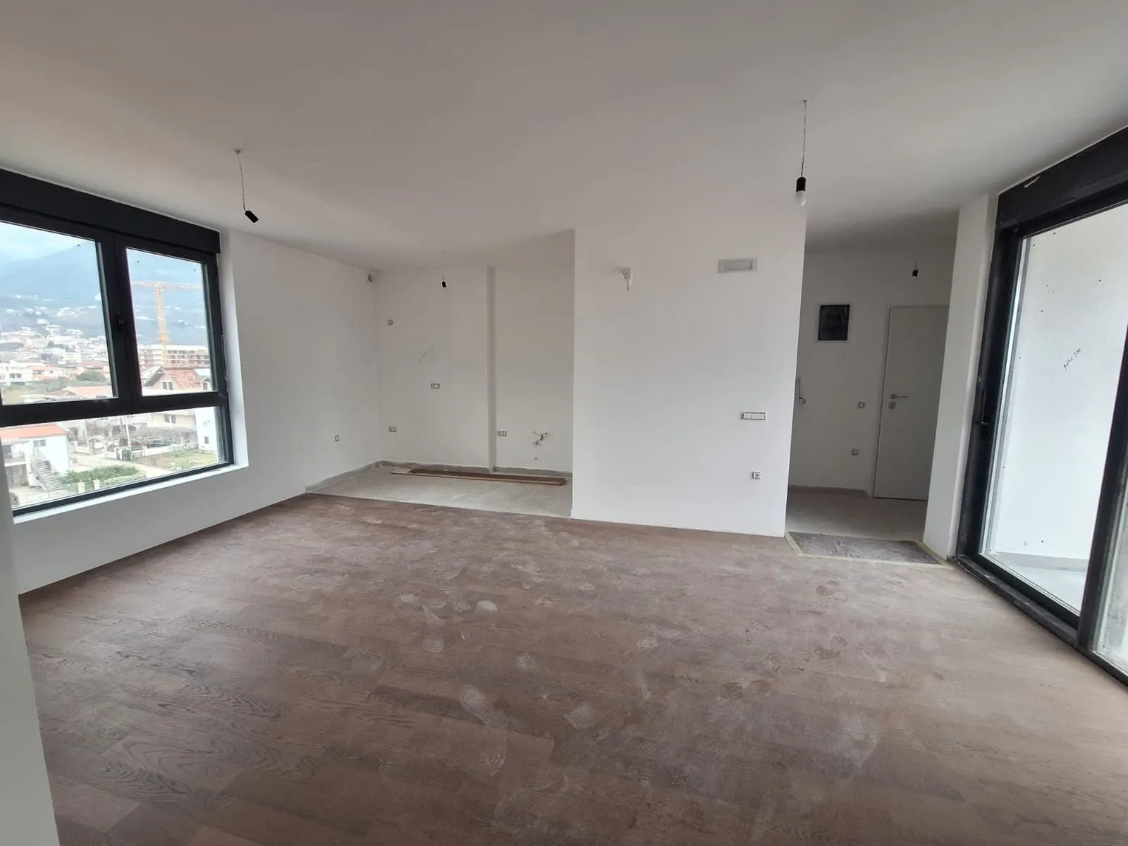 Unfinished modern living room with large windows and wooden flooring