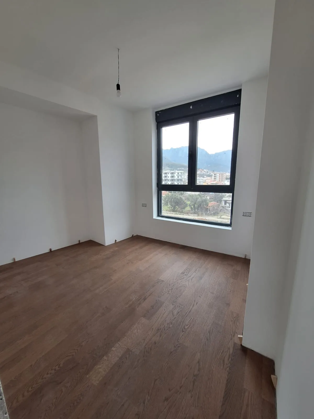 Empty room with hardwood floors and mountain view from window