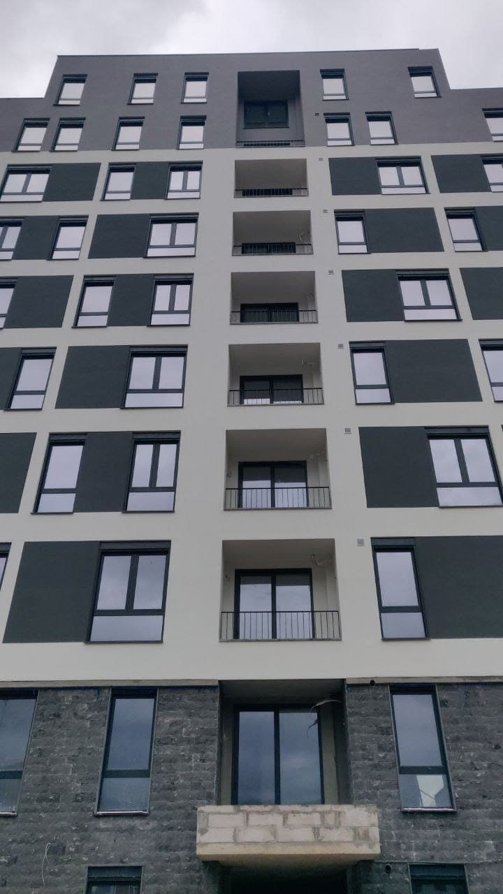 Karadağ, Bar şehrinde modern çok daireli bina: balkonlu ve panoramik pencereli cephe, alttan yukarıya görünüm.