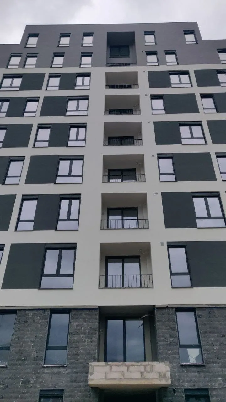 Facade of a multi-story residential building with many windows and balconies.