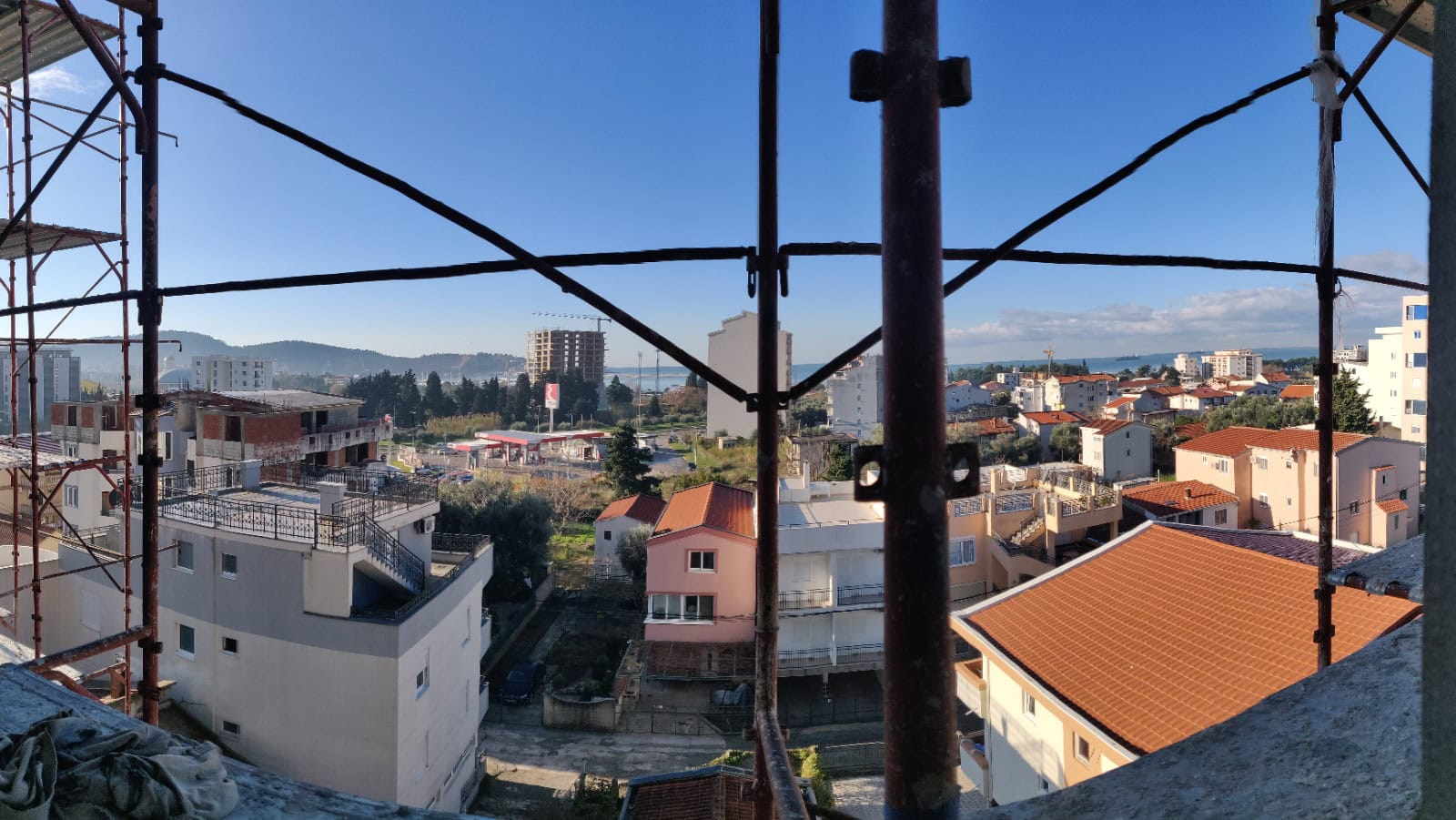 Karadağ’daki Bar şehrinin, inşaat halindeki bir binanın balkonundan görünümü; iskeleler arasından konut bölgesi ve uzakta deniz panoraması