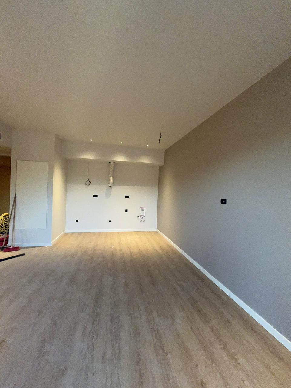 Ein leeres, unmöbliertes Zimmer mit hellen Holzböden und grauen Wänden.