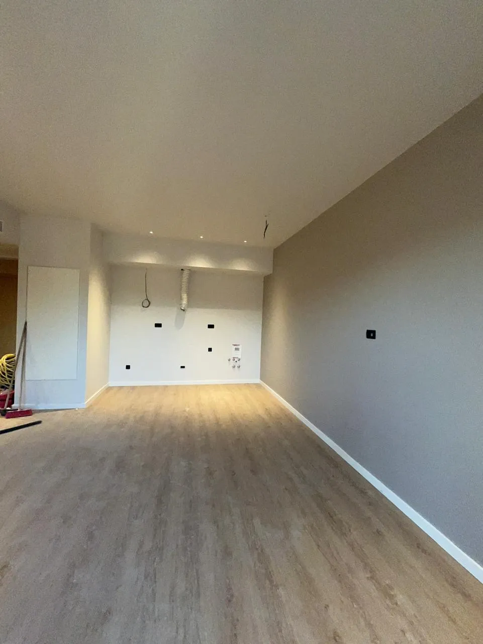 Ein leeres, unmöbliertes Zimmer mit hellen Holzböden und grauen Wänden.