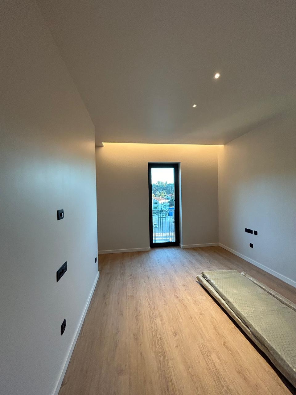 Heller Raum mit Balkontür und Holzfußboden.