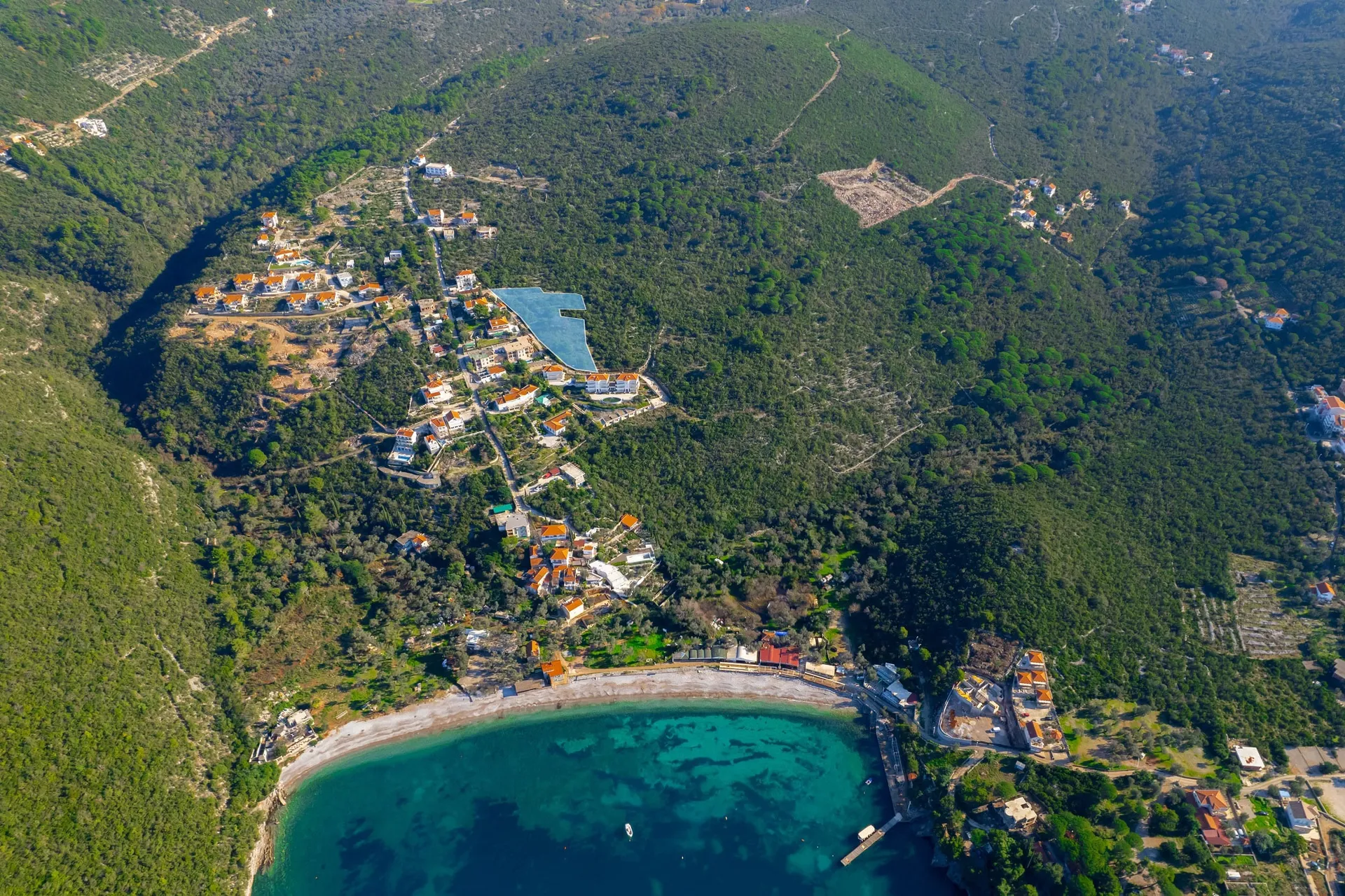 Plot of land #2390 in Žanjice, Montenegro: aerial view of the seaside plot surrounded by forests and villas.