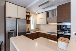 Moderne Küche in einer Villa in Bečići, Montenegro: Einbaugeräte, Hochglanzfronten und eine helle Arbeitsplatte.