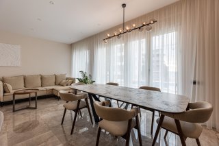 Modernes Wohnzimmer mit Essbereich in einer Villa in Bečići, Montenegro: Marmorboden, Designertisch und helle Möbel.