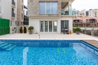Moderne Villa mit Pool und Terrasse in Bečići, Montenegro: Blick auf die Fassade des Hauses und den Erholungsbereich am Wasser.