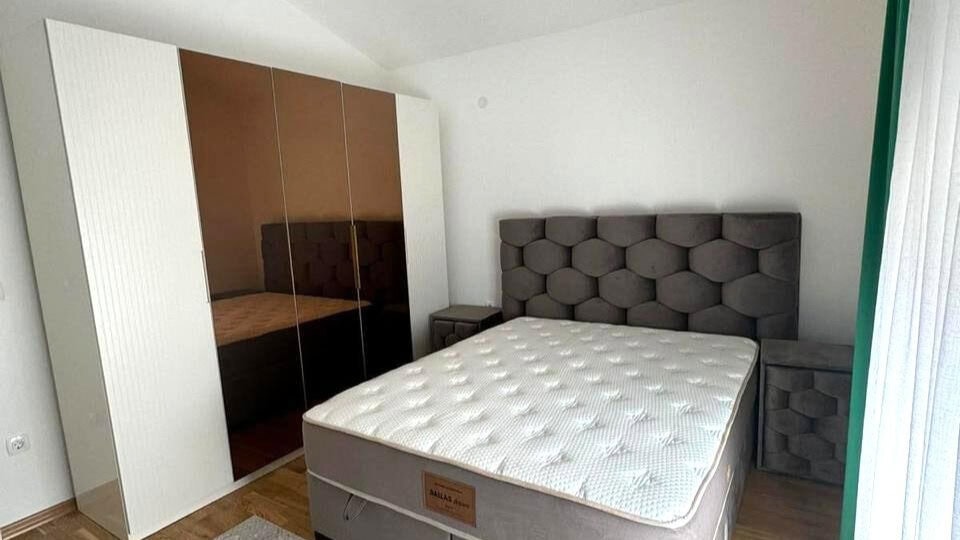 Schlafzimmer in einer Wohnung in Tivat, Montenegro: Doppelbett mit gepolstertem Kopfteil und Kleiderschrank mit Spiegelfronten.