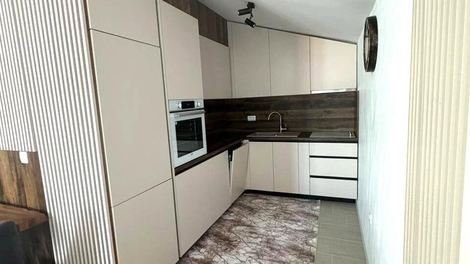 Moderne Küche in einer Wohnung in Tivat, Montenegro: helle Fronten, Einbaugeräte und Holzoptik.